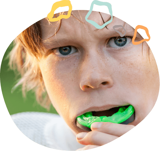 Young boy placing light green mouthguard over his teeth