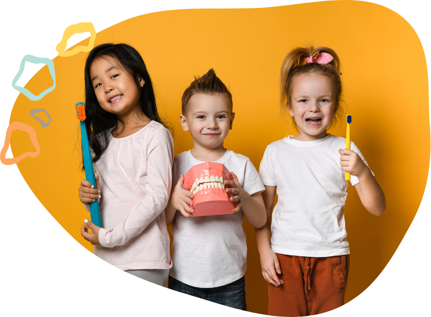 Three smiling kids holding oversized toothbrushes after visiting pediatric dentist in South Portland and Auburn