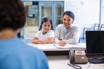 Woman and young daughter at dental office front desk