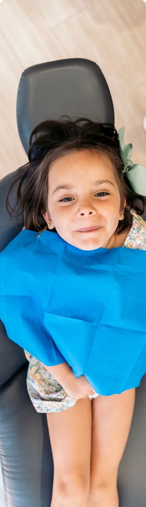 Young girl in dental chair looking up toward the camera