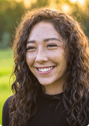 Teenage girl with long brown hair smiling outdoors